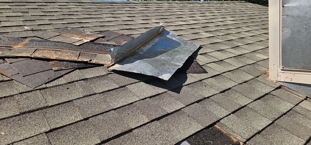 Damaged and displaced asphalt shingles after a storm